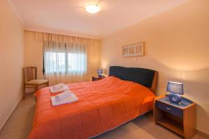 a bedroom with a orange bed and a table with a lamp at THERETRA KIOTARI VILLAS in Gennadi