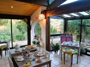 un comedor con mesas, sillas y ventanas en Chambre Indépendante Piscine, Parc, Cuisine... en Brézilhac