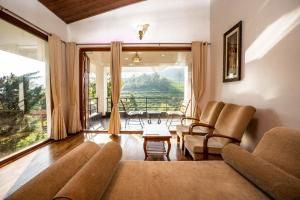 a living room with a couch and a large window at Green Nest Resort Ooty in Kotagiri