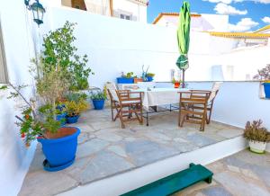 a patio with a table and chairs and potted plants at Ύδρα ivY in Hydra +2 photos