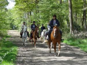 a group of people riding horses down a dirt road at Les Roulottes de la Risle in Calleville