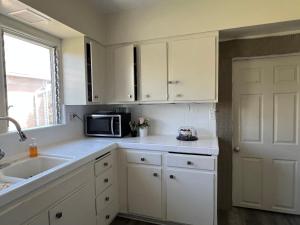 a kitchen with white cabinets and a sink and a microwave at UCLA Westwood in Los Angeles