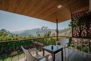 Green Nest Resort Ooty في كوتاغيري: غرفة مع طاولة وكراسي على شرفة