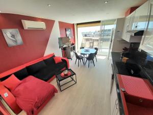 sala de estar con sofá rojo y mesa en Appartement Village Naturiste Passion, en Cap d'Agde