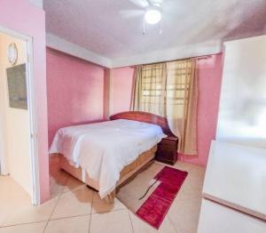 a pink bedroom with a bed and a window at Arliebev apartments 2 in Mahaut