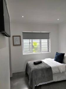 a white bedroom with a bed and a window at Harbour View House in Durban