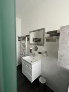 Baño blanco con lavabo y espejo en LEA Apartments Waldstraßenviertel, en Leipzig