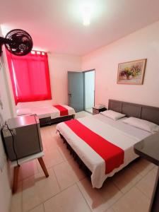 een slaapkamer met 2 bedden en een rood raam bij Hotel Gueicer Cucuta in Cúcuta
