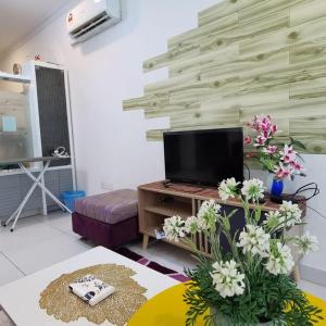 a living room with a tv and flowers on a table at IMAN HOMESTAY : PRIMA HOMES MATANG APARTMENT in Kampung Gita