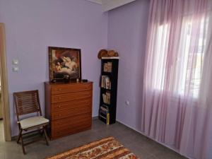 um quarto com uma cómoda, uma cadeira e uma janela em Giannis country house em Palaiokómi