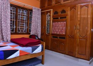 a bedroom with a bed and wooden cabinets at Sri Kaveri Homestay in Madikeri