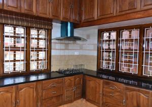uma cozinha com armários de madeira, balcões e janelas em Sri Kaveri Homestay em Madikeri
