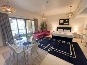 Charming spacious studio apartment in the heart of JBR By SWEET HOMES في دبي: غرفة معيشة مع سرير وطاولة وكراسي