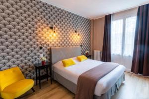 リジューにあるルテル デ レスペランスのベッドと黄色い椅子が備わるホテルルームです。