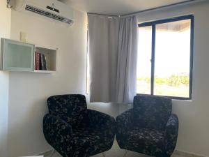 two chairs sitting in a room with a window at Hotel Victory flat in Cabedelo