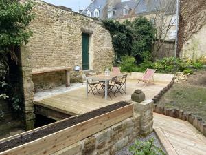 a patio with a table and chairs on a wooden deck at Appartement centre-ville de Valognes in Valognes