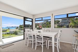 Un comedor con mesa y sillas y ventanas. en Retreat at Tapeka Point - Russell Holiday Home, en Russell