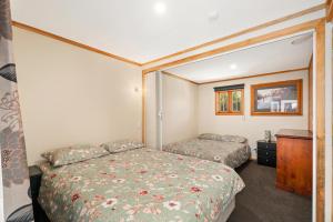 a bedroom with two beds and a mirror at Albert Town Bach - Wanaka Holiday Home in Wanaka