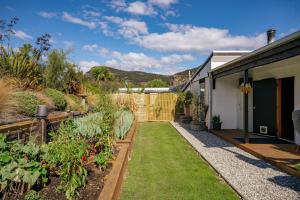 a garden with plants and a house at Albert Town Bach - Wanaka Holiday Home in Wanaka