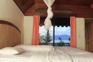 a bedroom with a bed and a large window at SONY COTTAGE in Tuk Tuk