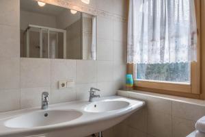 a white bathroom with two sinks and a window at Adlerhorst Rotkehlchen in Santa Valpurga