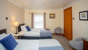 a hotel room with two beds and a chair at Redesdale Arms in Otterburn