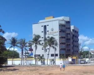 two people standing in front of a large building at Hotel Victory flat in Cabedelo