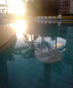 uma piscina com o sol refletindo na água em Hotel Victory flat em Cabedelo