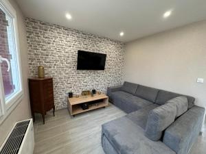 a living room with a couch and a tv on a brick wall at Agréable maison avec jardin à Joinville in Joinville