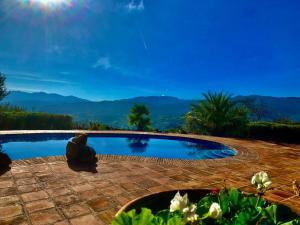 une personne assise à côté d'une piscine dans l'établissement Villa & Poolhouse with Private Pool 360 degrees view 'Spinola' in pure nature, à Alozaina