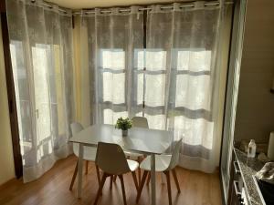 una mesa de comedor blanca y sillas frente a una ventana en Casa Leonor en Soto de Luiña