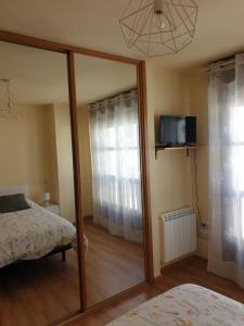 a mirror in a bedroom with a bed and a tv at Casa Leonor in Soto de Luiña