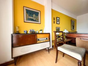 a living room with a dresser and a chair and a piano at Amplio Piso Vintage, Terraza con Vista a Sierras in Cordoba +9 photos