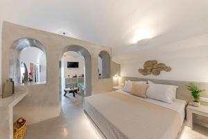 ein Schlafzimmer mit einem großen weißen Bett in einem Zimmer in der Unterkunft Kaleidoscope Imerovigli Suites in Imerovigli