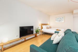a living room with a green couch and a flat screen tv at Dream On - Clérigos Lofts in Porto