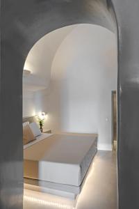 a bedroom with a bed and an archway at Kaleidoscope Imerovigli Suites in Imerovigli