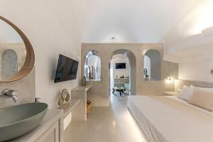 ein Bad mit einem Bett, einem Waschbecken und einem Spiegel in der Unterkunft Kaleidoscope Imerovigli Suites in Imerovigli