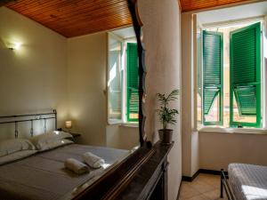 a bedroom with a bed and windows with green shutters at Macaia Room #1 Vernazza in Vernazza