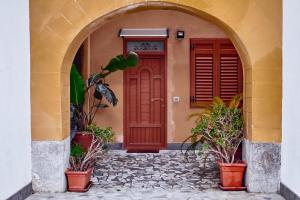 una entrada a una casa con puerta roja y macetas en Palermo al Centro - Appartamento Maestri en Palermo