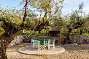 una mesa y sillas frente a una chimenea en Stoupa Serene Nests - Spitiko Getaway, en Stoupa