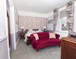 ein Wohnzimmer mit einem roten Sofa und einem Bett in der Unterkunft Beaumont Guest House - FREE off-site Health Club - Adults Only in Windermere