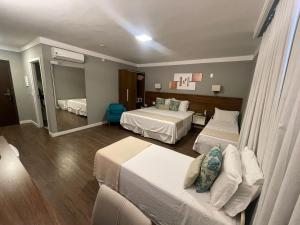 a hotel room with two beds and a mirror at Hotel Villa Fiori in Poços de Caldas