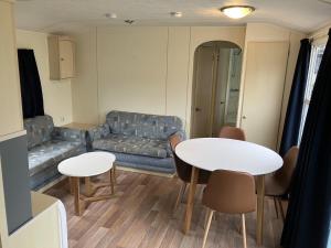 een woonkamer met een bank en een tafel en stoelen bij Vakantiepark Klein Vink - 190 in Arcen