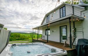 un bain à remous sur une terrasse en face d'une maison dans l'établissement Les Chalets Tourisma - Maison de campagne avec spa - La Campagnarde, à Saint-Raymond