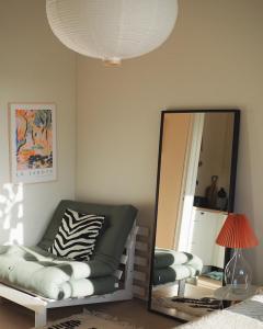 um espelho numa sala de estar com um sofá e uma cadeira em Beautiful design studio in the heart of Kallio em Helsinque