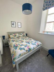 a bedroom with a bed with a floral bedspread at Premium apartment in a peaceful location with great views. in Inverness