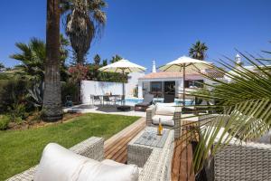 een patio met stoelen en parasols in de achtertuin bij Casa Girassol in Carvoeiro