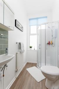 a white bathroom with a shower and a toilet at Flatzy - Huge 7 Bed House Close to Football Stadiums in Liverpool