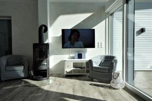 a living room with a flat screen tv and a chair and a fireplace at Witte Bank in Büsum