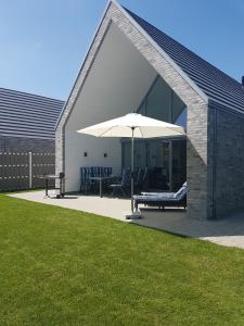 a patio with an umbrella and a table and bench at Witte Bank in Büsum